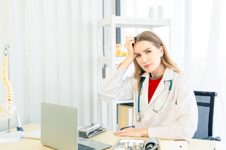 A female beautiful doctor is wearing a doctor uniform have a stethoscope doing a headache or stressed posture case of treatment in the examination room in the hospital or clinic.の写真素材