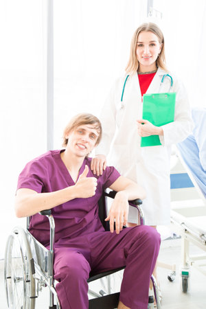 The male patient wearing in a patient dress in a wheelchair seemed happy to recover from illness or to go home in a hospital or clinic room.の写真素材