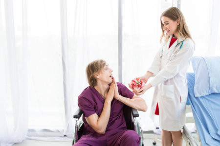 A Female beautiful doctor is wearing a uniform give a gift box to the patient in a wheelchair on a...