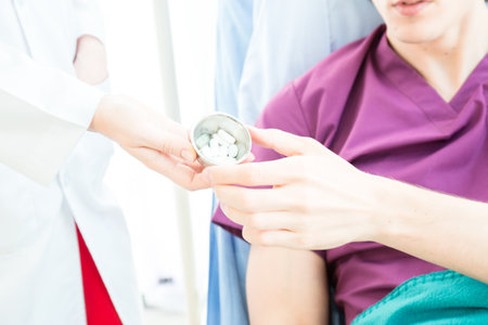A Female doctor is wearing a uniform give a drug to the patient in a bed in hospital or clinic room.の写真素材