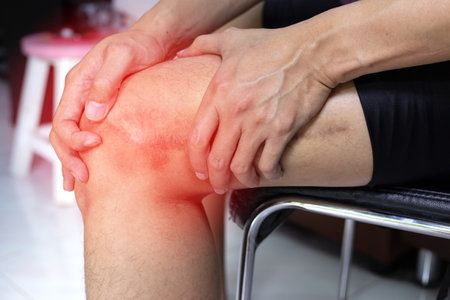 Man puts hands on knee in pain from surgery woundの写真素材