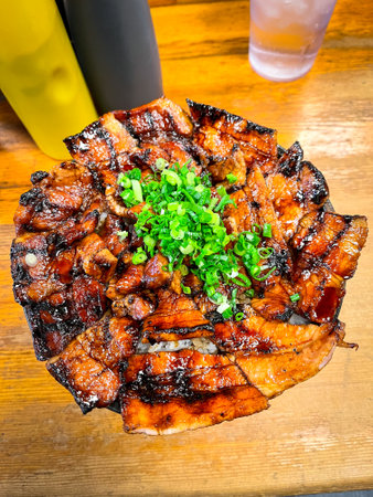 A plate of bacon and onions sits on a wooden table. The bacon is cooked and he is grilled, and the onions are chopped and sprinkled on top. The dish looks delicious and appetizingの写真素材