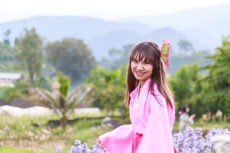 A woman in a pink traditional outfit posing elegantly amidst blooming lavender flowers.の写真素材