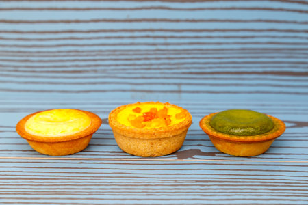 Mango tart, Egg tart and Steamed custard tart on a wood with copy space.の写真素材
