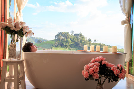 A serene moment soaking in a bath with stunning hillside views, surrounded by roses and candlelight.の写真素材