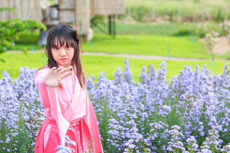 A woman in a pink traditional outfit posing elegantly amidst blooming lavender flowers.の写真素材