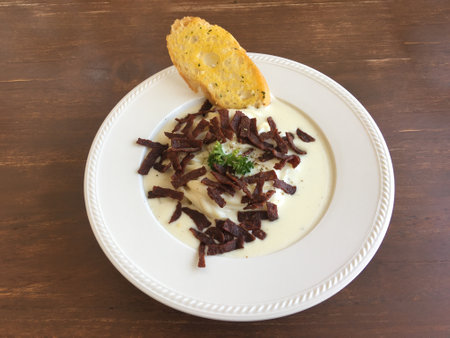 Spaghetti carbonara cream topped with crispy bacon served with butter bread in a white ceramic plant on a wooden table in the restaurant. top view.の写真素材