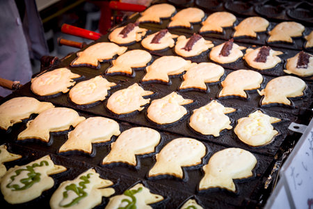 Delicious taiyaki: Fish-shaped pastry filled with red bean and green tea. A popular Japanese treat cooked on an iron pan.の写真素材