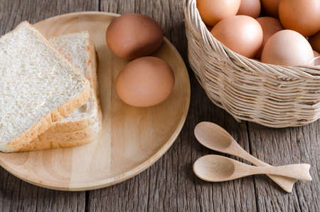 Top view closeup eggs and bread with basket and wooden spoonの写真素材