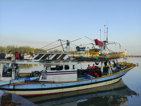 a dominant blue boat anchored in a traditional harbor on the coast of Paiton, Probolinggo, East...