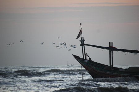 a wooden ship anchored on the shore of a cloudy sunsetの写真素材