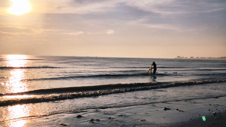 silhouette of a fisherman catching fish on the beachの写真素材