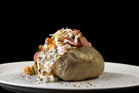 Stuffed baked potato on plate isolated on black backgroundの写真素材
