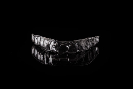 Transparent clear aligner orthodontic upper splint on black background close up