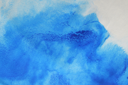 Abstract hand painted blue watercolor splash on white paper backgroundの写真素材