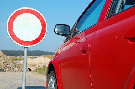 Car has stopped in front of a road sign. A barrier is ahead.の写真素材