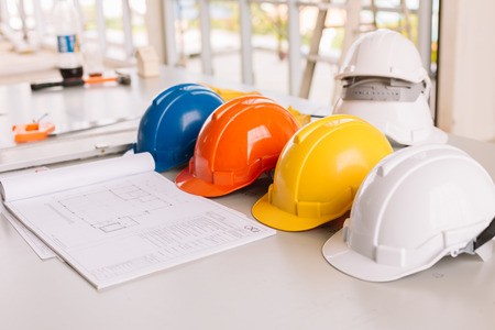 Yellow,white, Blue, Orange helmet safety engineer for project engineering.On the floor of the desk.の写真素材