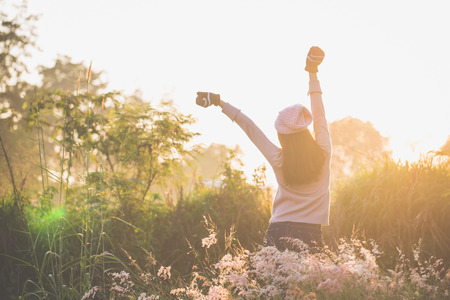 Winter and spring, Young woman standing outdoor with warm clothes and gloves and  earmuff with a holding hands up on a warm morning background.の写真素材