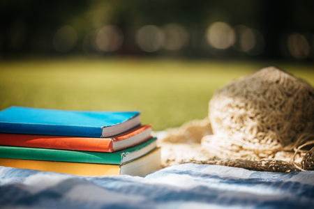 Education learning concept - Book stacked with a hat on blue cloth and green lawn.の写真素材