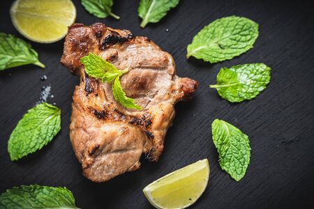 Beef steak is placed on a black background with mint leaves.Top view.の写真素材
