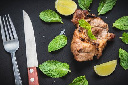 Beef steak is placed on a black background with mint leaves.Top view.の写真素材