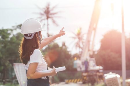 Portrait of engineer woman looking for construction, Asian female architect with blueprints standing on the background of construction work, Engineering and architecture concept.の写真素材
