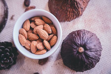 Health food concept - Top view almonds in a white cup on a wooden table with a cocoa effect on the side.の写真素材