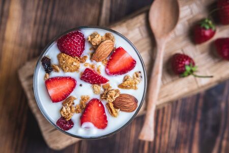 Health concept - Yogurt and strawberries on a wooden table, Homemade granola. Top view.の写真素材