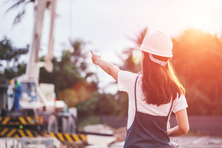 Portrait of engineer woman looking for construction, Asian female architect with blueprints standing on the background of construction work, Engineering and architecture concept.の写真素材