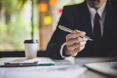 Businessmen at work. Close up CEO holding a pen to sit on the desk to analyze and present economic problems. working day in office.の写真素材