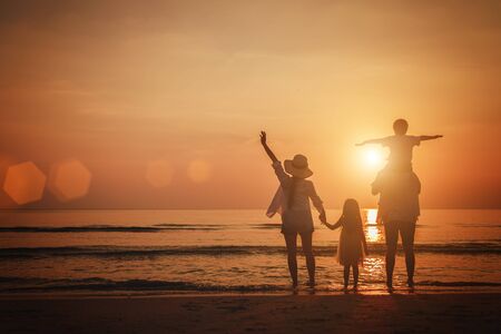 Summer vacation, Happy family  together on the beach in holiday. Silhouette of the family holding hands enjoying the sunset on the tropical beach.の写真素材