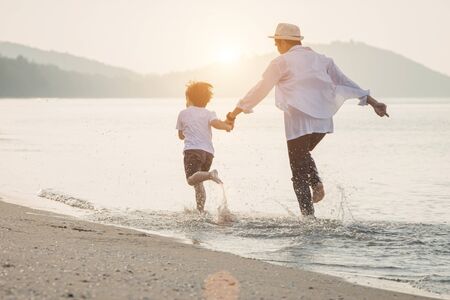 Happy family with little boy walking together on a tropical beach during the summer holidays. Happy father and son running on the beach in the morning.の写真素材