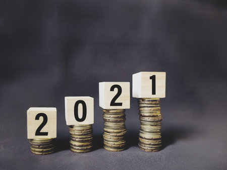 2021 number written on wooden blocks on top of coins stacks background. Business concept. Stock...