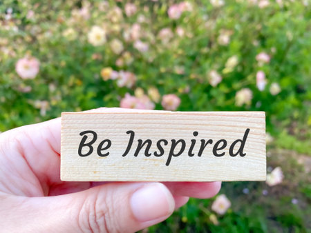 Be Inspired written on wooden block in hand with blurred background. Motivational and inspirational quoteの写真素材