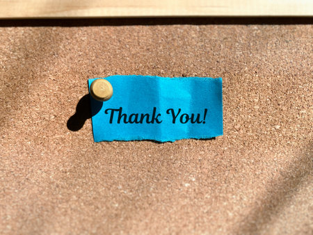 Thank You message on a blue paper attached to a cork boardの写真素材