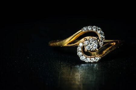 Macro shot of a golden diamond ring kept in the right in a dark background. Space for text in the leftの写真素材