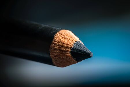 A macro shot of a black pencil tip. Kept in a blue backgroundの写真素材