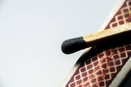 Isolated match stick kept over the edge of a matchbox in a white background. Space for text in leftの写真素材