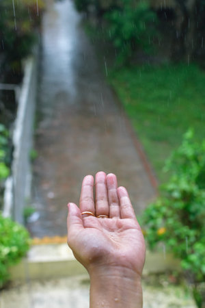 Isolated wet human hand with rain drops falling on it. Portrait view