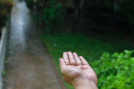 Isolated wet human hand with rain drops falling on itの写真素材