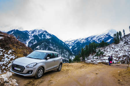 A car is parked and snow capped mountain peaks are visible in the backgroundのeditorial素材