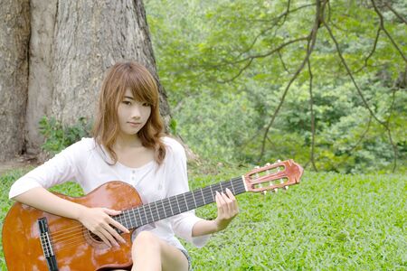 Thai cute girl with nylon string guitar in the garden 2の写真素材