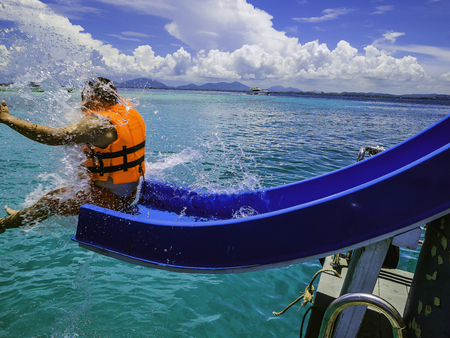 Asian man playing the slider on the boat with amzing idyllic ocean and Blue in vacation time.Summer concept.travel conceptの写真素材