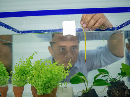 Asian guy use thermometer check water temperature in the fish tank