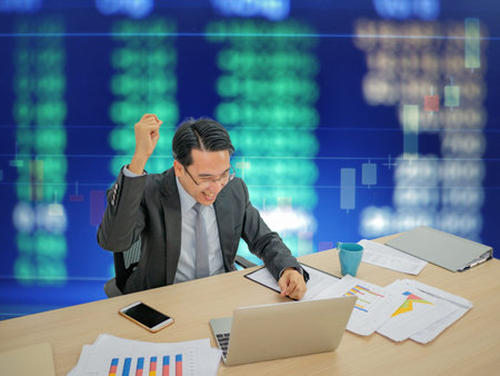 Asian business man sitting very happy becuase his stock market growth up,business man sitting on his...
