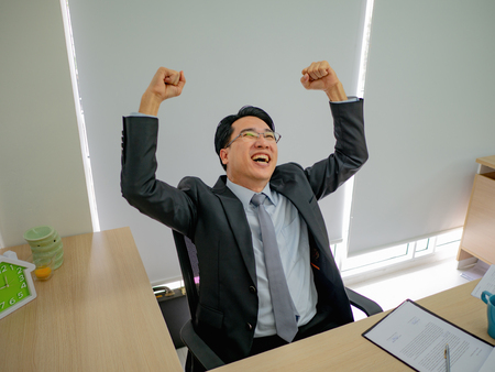 Very Happy asian business man sitting on his desk,business conceptの写真素材