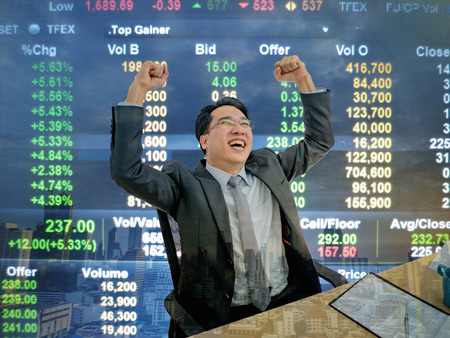 Asian business man sitting very happy becuase his stock market growth up,business man sitting on his desk with stock market background,business concept
の写真素材