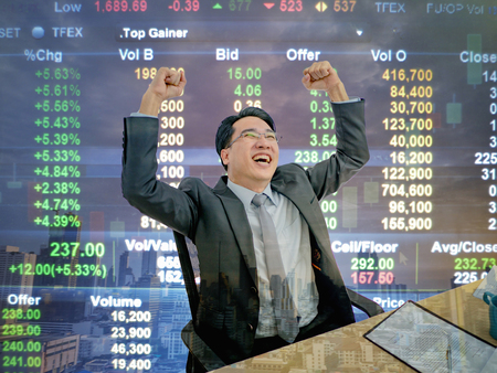 Asian business man sitting very happy becuase his stock market growth up,business man sitting on his desk with stock market background,business concept
の写真素材