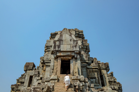 Asian women climb up to Ancient stone castle in Angkor wat Angkor Thom,wonder of the worldの写真素材