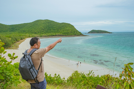Asian fatty backpacker stand on view point on top of the island with idyllice beach ocean and blue sky in vacation time,Samae San Island chonburi thailand,summer conceptの写真素材